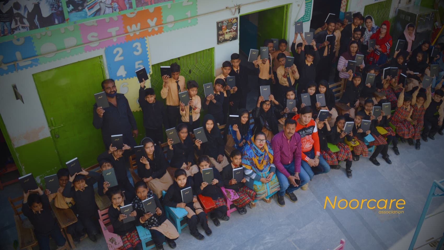 A classroom of children in Pakistan holding up their books